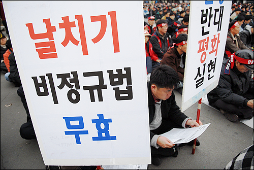 한 노동자가 '날치기 비정규법 무효'라는 알림판 뒤로 총파업선전물을 읽고 있다. 